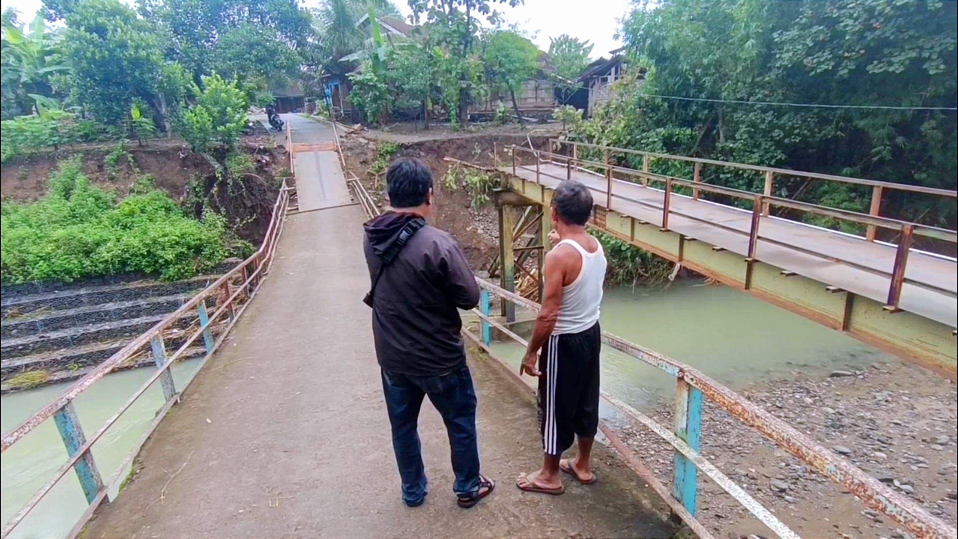 Warga yang tengah menunjukkan jembatan yang putus