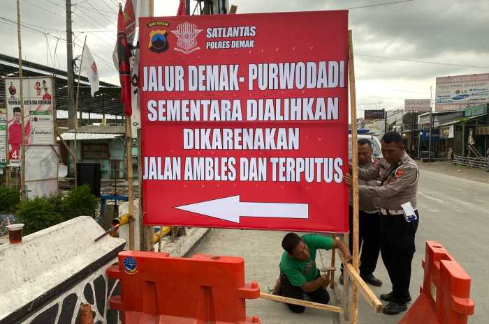 Petugas Satlantas Polres Demak memasang papan pengumuman pengalihan arus kendaraan di Karangawen. (Wahib Pribadi/Jawa Pos Radar Semarang)