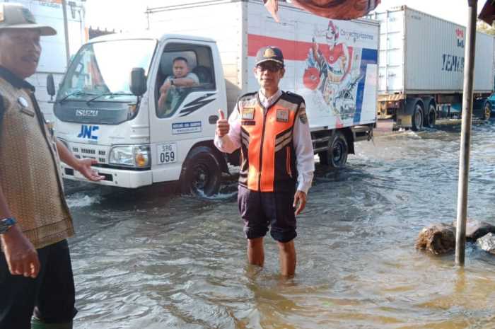 Camat Mijen Purkanto (kiri) memantau ketikggian air di jalan raya Mijen-Welahan yang kebanjiran. (Wahib&nbsp;Pribadi/Jawa Pos Radar Semarang)