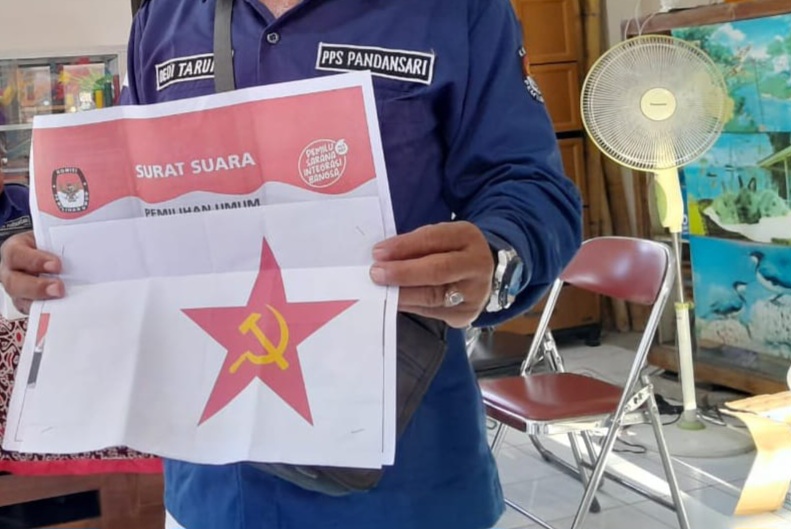 Petugas menunjukkan kertas suara yang ditempeli gambar palu arit di TPS Pandansari Semarang. (M Hariyanto/Jawa Pos Radar Semarang)
