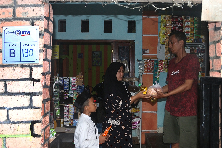 Edi Sulaiman saat melayani pembeli Sembako di halaman rumah yang di manfaatkan untuk berjualan di Perumnas Bumi Palir Sejahtera,Kota Semarang(15/2/2024).