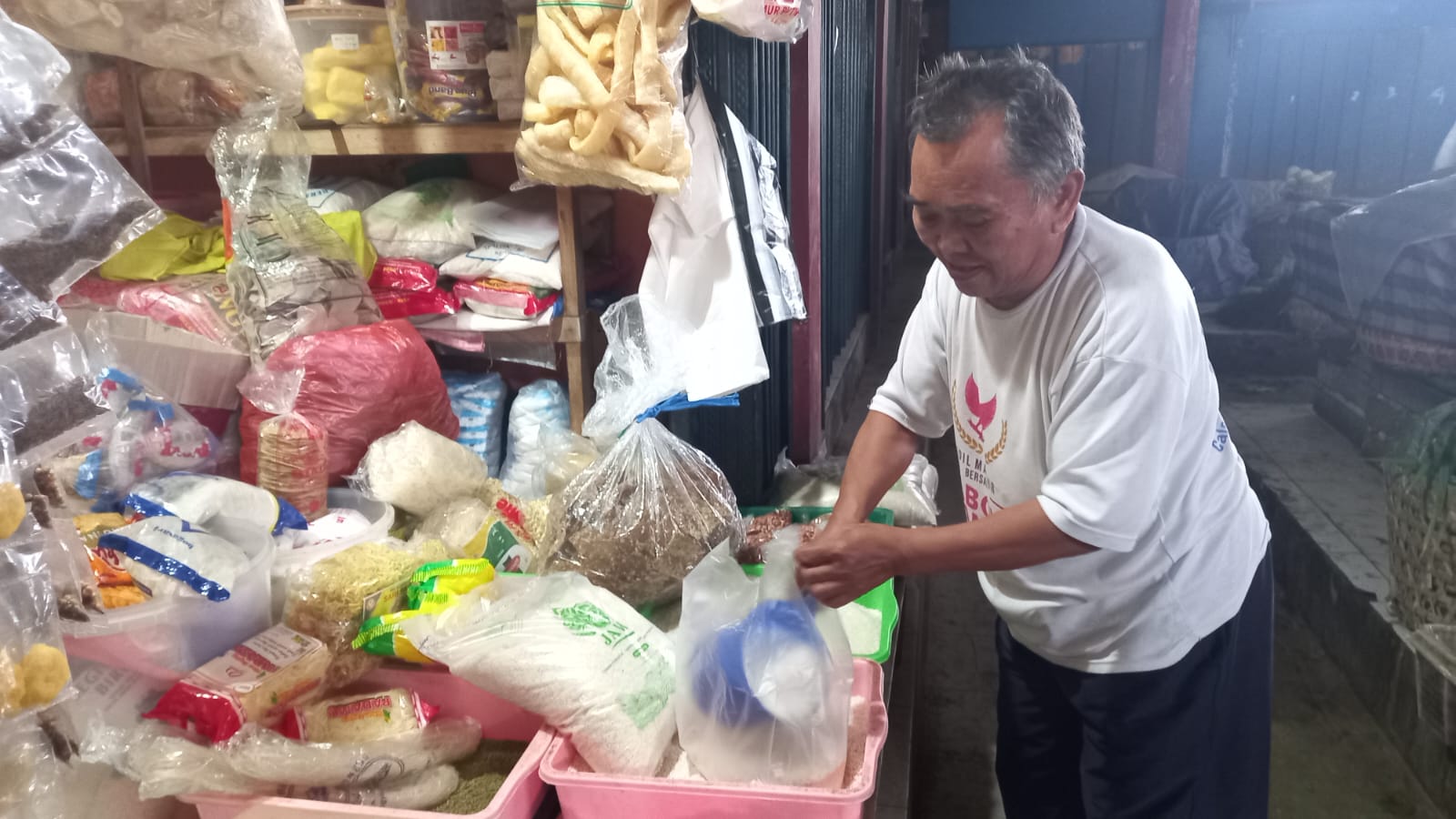 Slamet saat hendak melayani pembeli yang membeli beras di kiosnya