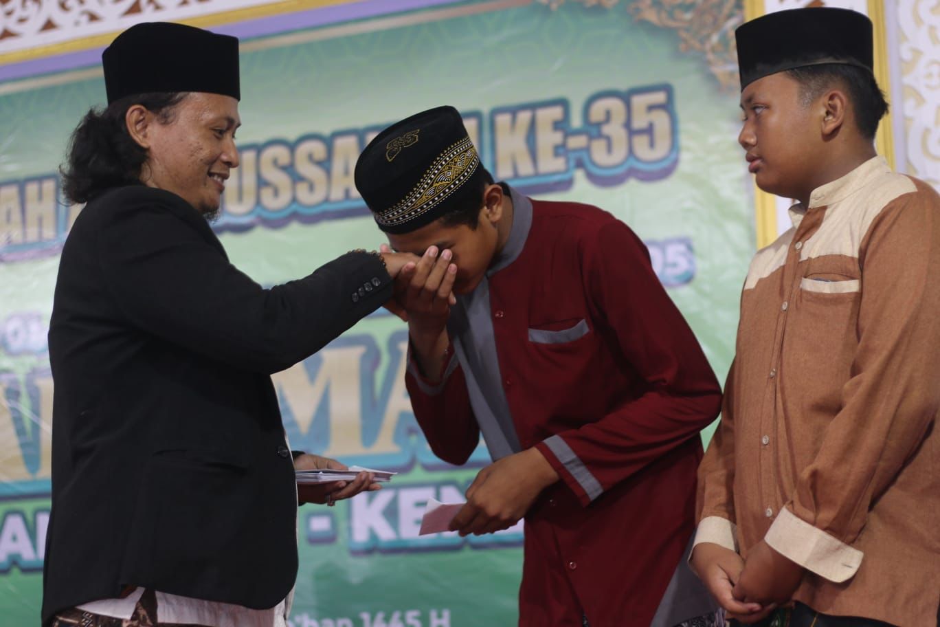 Kades Brangsong Moh Asnawi saat memberikan hadiah untuk siswa Madin berprestasi.