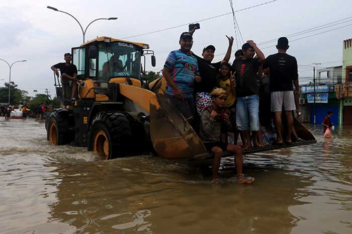 Alat berat buldoser dikerahkan untuk mengevakuasi warga yang terjebak banjir di Jalan Kaligawe Raya, Kota Semarang Kamis (14/3). NURCHAMIM/JAWA POS RADAR SEMARANG