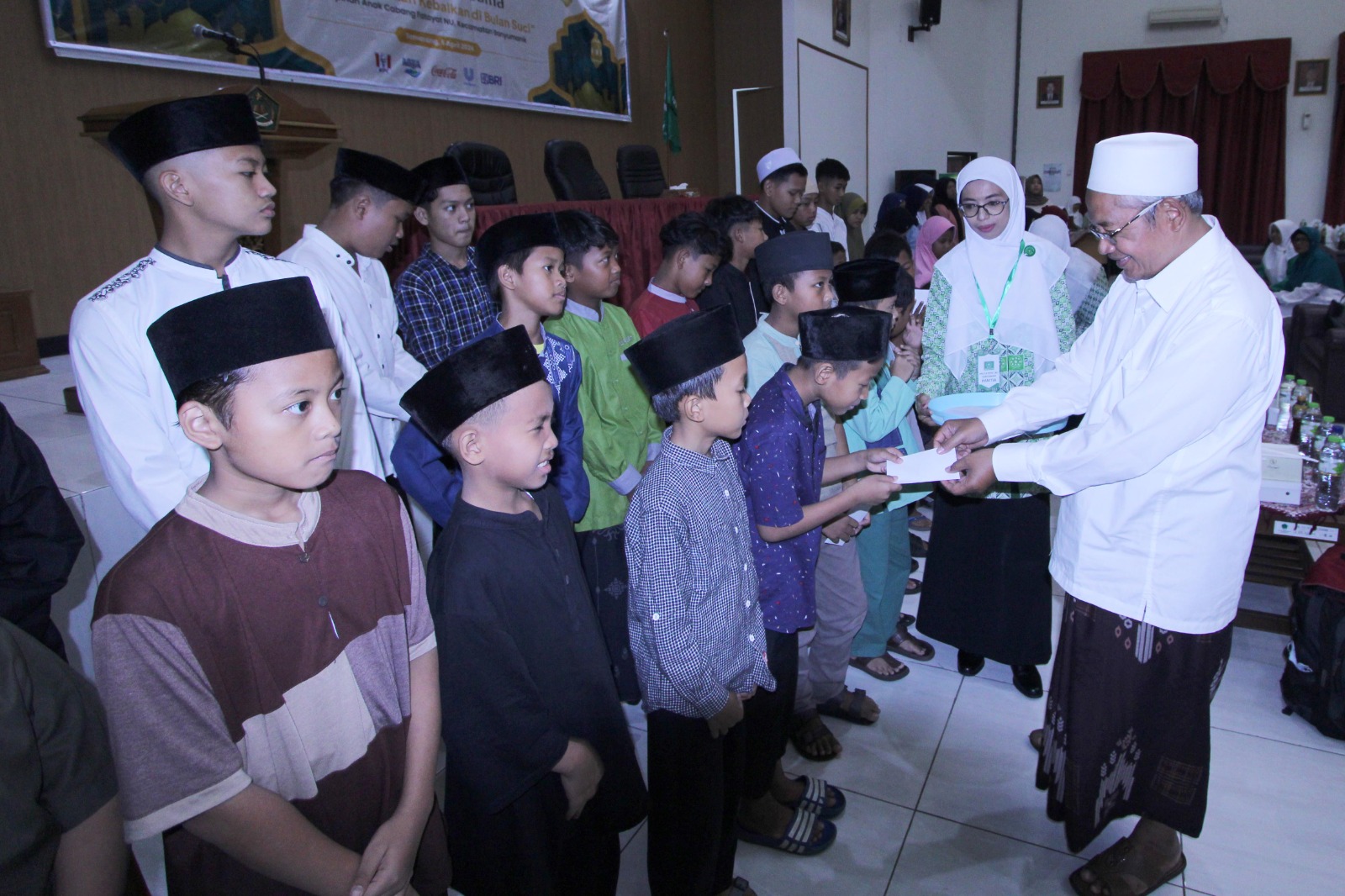 BUKBER : Rois Syuriah MWC NU Banyumanik, KH Aminuddin, memberikan santunan kepada anak yatim piatu dan dhuafa saat buka puasa bersama di BDK Kemenag di Kota Semarang, Sabtu 6 April 2024.