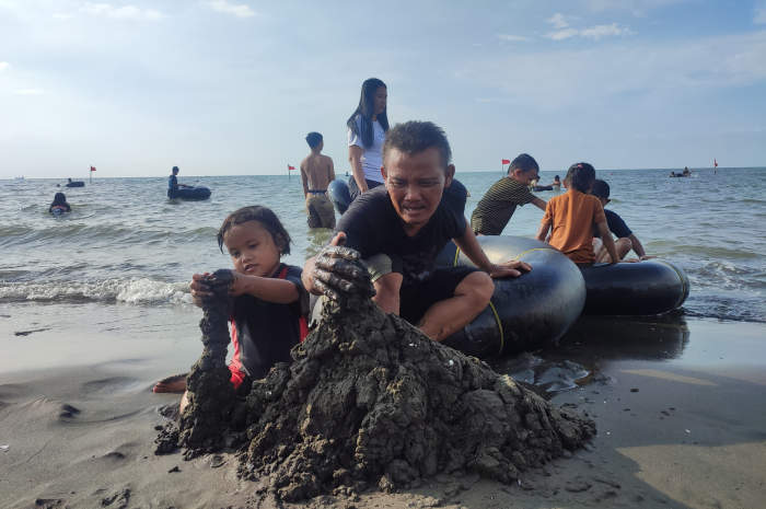 Sutarto asyik bermain pasir bersama sang anak di Pantai Tirang, Jumat (12/4/2024). IDA FADILAH/JAWA POS RADAR SEMARANG