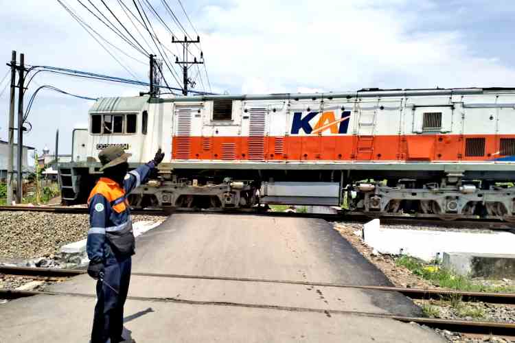 Petugas dari PT KAI Daop 4, Akbar sedang mengatur lalu lintas di perlintasan rel kereta api tanpa palang pintu Jalan Purwosari-Tanggungre