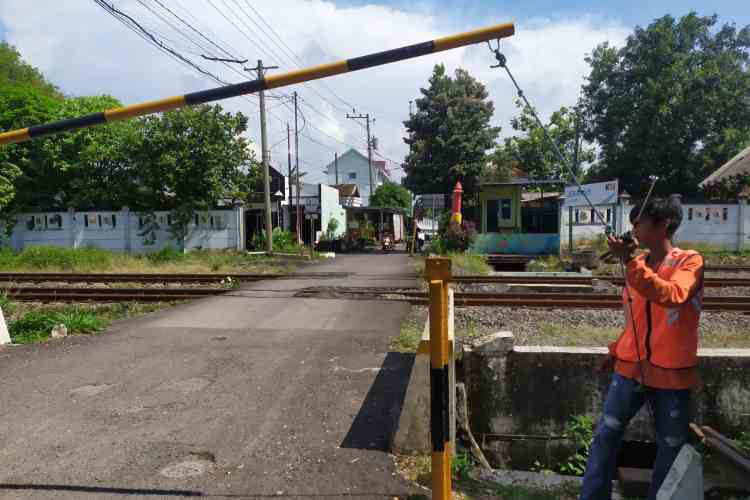 BERJAGA: Jack, 25, saat berjaga di palang pintu perlintasan rel KA di di wilayah Tambakharjo, Semarang Barat.
