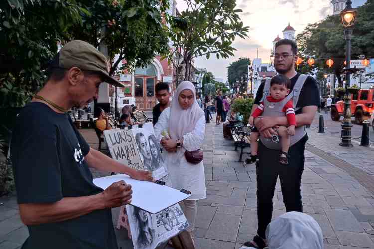 PELUKIS CEPAT : Pelukis jalanan Yoyok Barokallah saat melukis wisatawan di Kota Lama saat momen liburan Idul Fitri 1445 Hijriah.