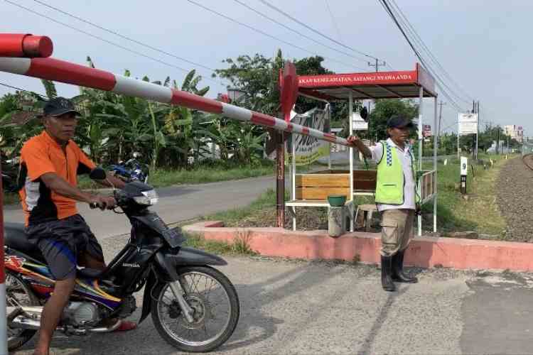 Mujiono, 55, saat menjaga perlintasan kereta api di Desa Pagerdawung, Ringinarum.