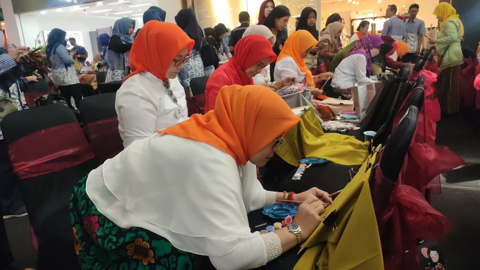 Seorang perserta lomba serius menuangkan ide lukisan diatas hijab