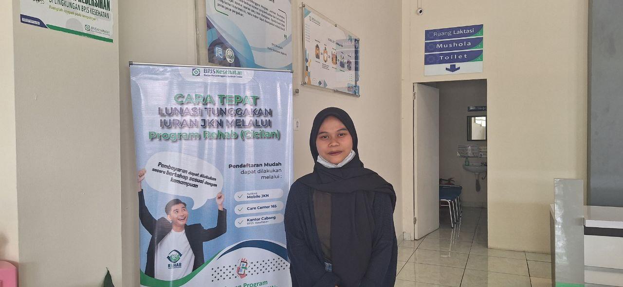 Sela menunjukkan kartu JKN ketika mengurus pendaftaran anak pertamanya menjadi peserta JKN. (Dokumentasi BPJS Kesehatan Cabang Magelang)