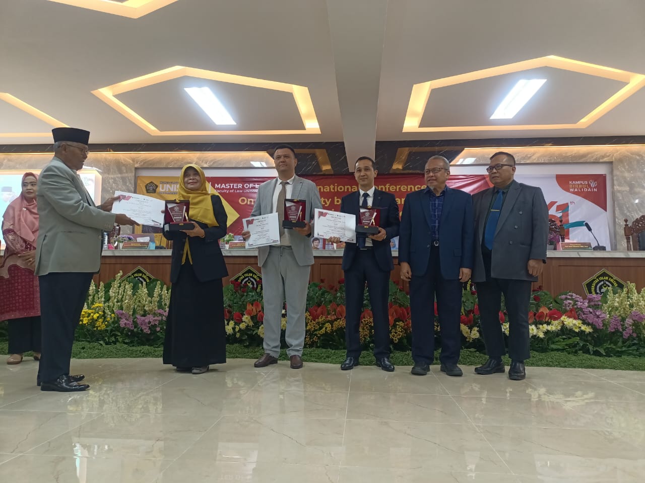 Ketua Pembina YBWSA Azhar Combo (kiri) menyerahkan cinderamata ke pembicara didampingi Rektor Unissula Prof Gunarto dan Dekan FH Unissula Dr Jawade Hafidz, Sabtu (18/5).
