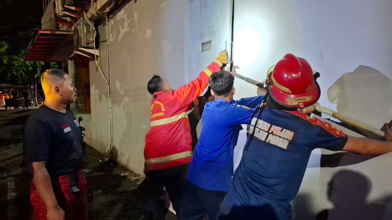 Petugas Damkar saat berusaha membobol pintu untuk menjangkau titik api di Kantor Cabang BNI Kendal yang terbakar.