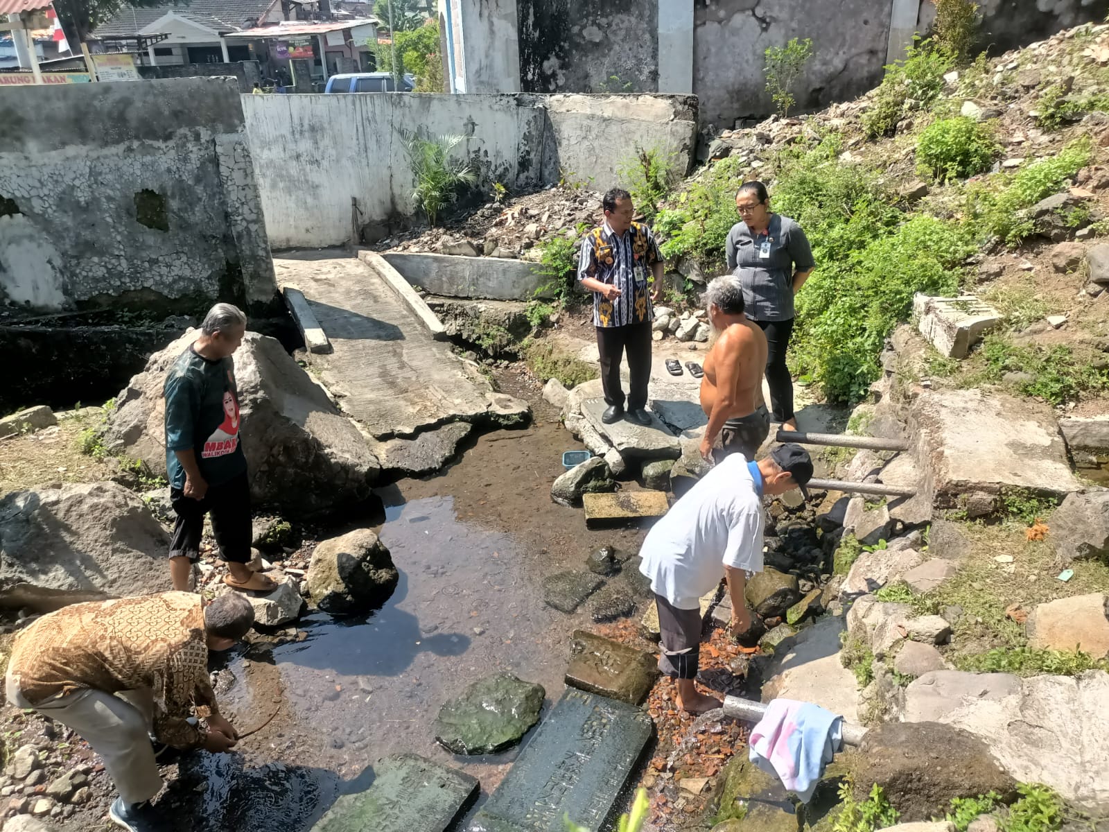 BEKAS NISAN : Sejumlah warga memanfaatkan air di Sendang Stoom yang dipenuhi batu bekas bongpay.