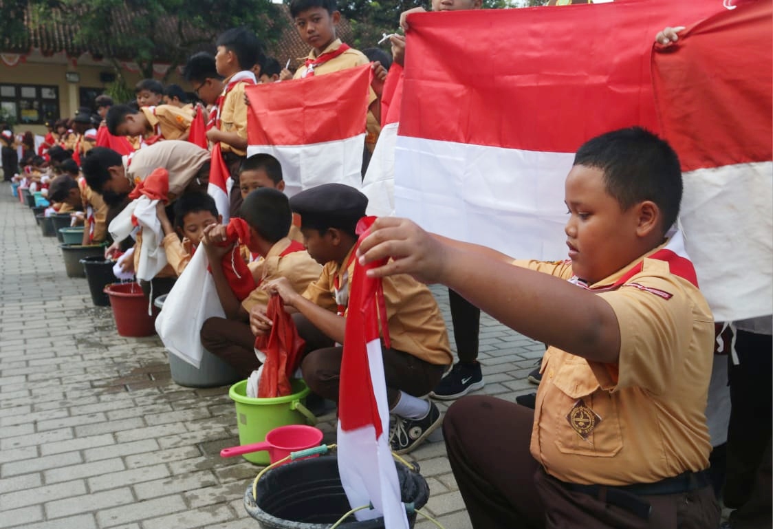 NASIONALME : Siswa SDN Jatisari mencuci bendera merah putih saat Kemah Karakter, Selasa (13/8/2024)