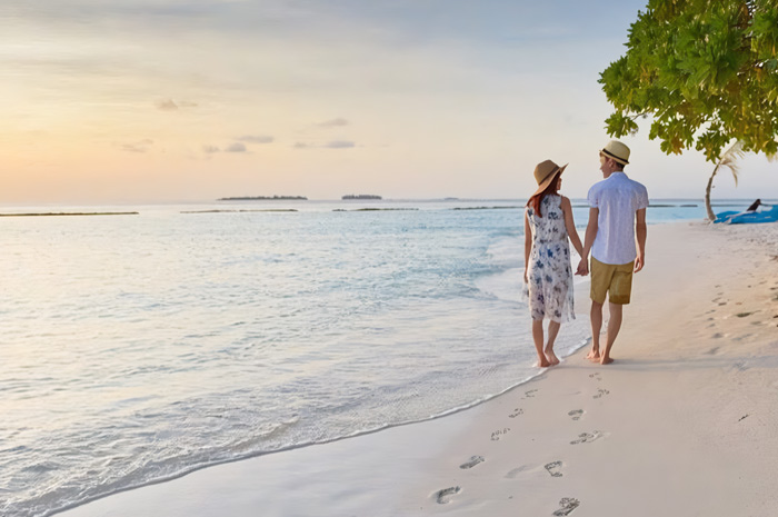 Ilustrasi pasangan baru saat honeymoon di pantai.