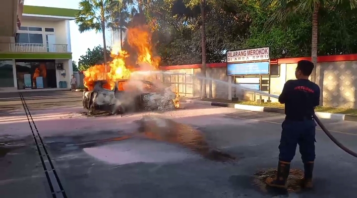 Petugas menyemprotkan air ke arah mobil yang terbakar di SPBU Mranak Kota Demak. (wahibpribadi)