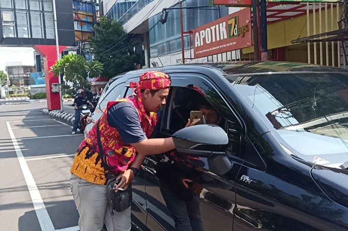 Juru parkir di Jalan Thamrin, ketika menerima pembayaran non tunai dari pengguna jalan.