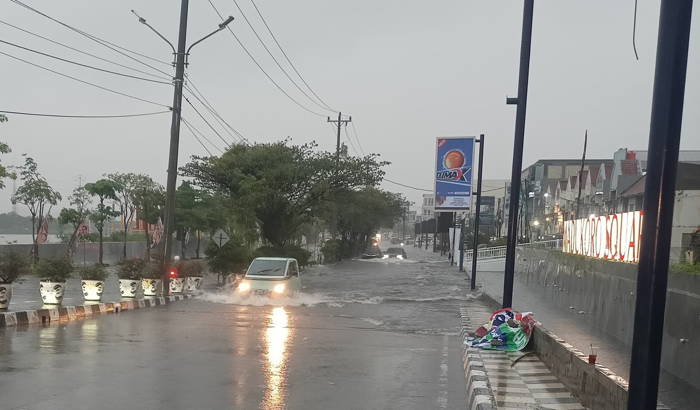Sebuah mobil nekat menerobos genangan air di Jalan Madukoro, Kota Semarang yang banjir Selasa (19/11/2024).