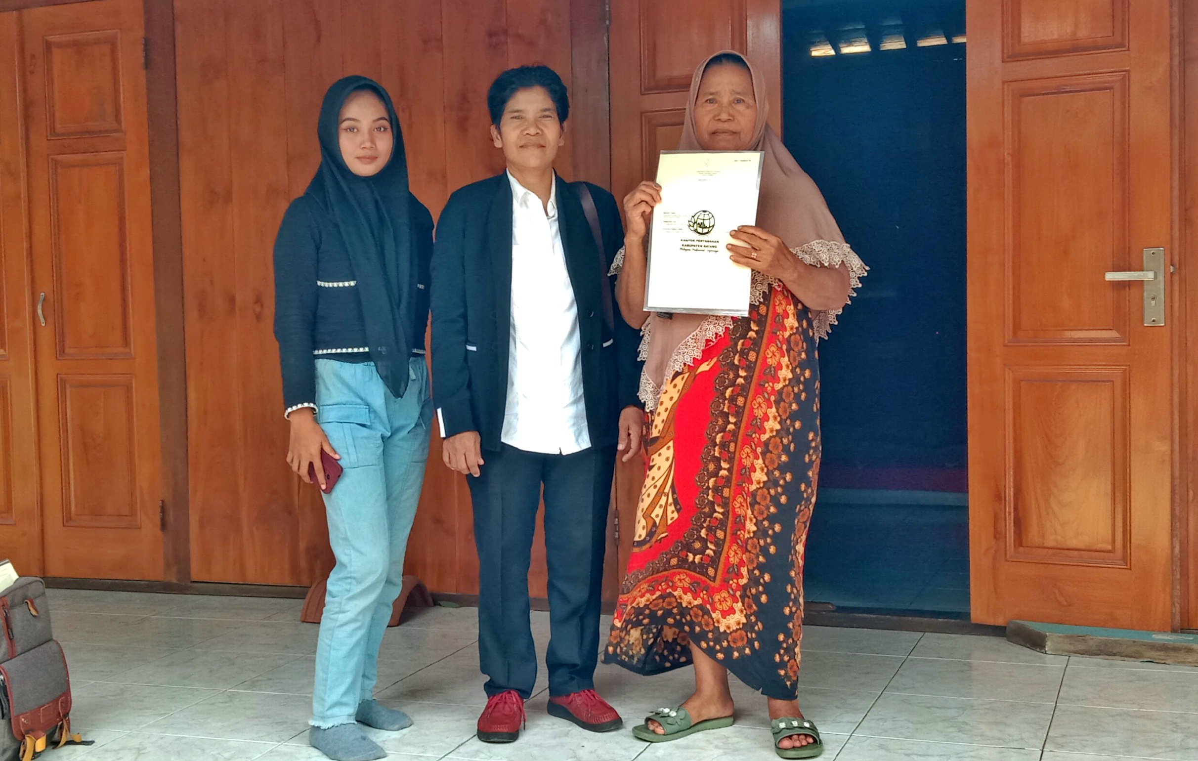 TUNJUKKAN SERTIFIKAT : Rusinah warga desa Yosorejo Kecamatan Gringsing menunjukkan sertifikat miliknya didampingi ketua panitia PTSL Ragil, Senin (30/12/2024).
