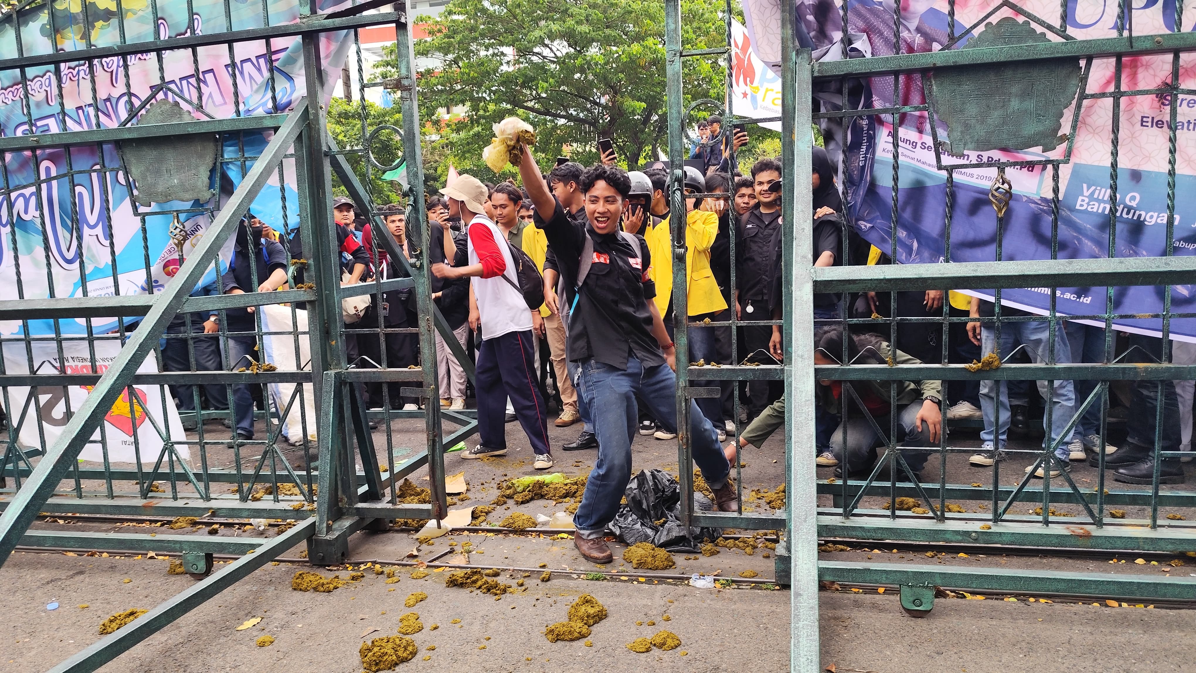Peserta demo menyebar kotoran sapi di gerbang kantor DPRD Jateny yang dijaga aparat kepolisian, Selasa (18/2/2025) sore.  (M Hariyanto/Jawa Pos Radar Semarang)