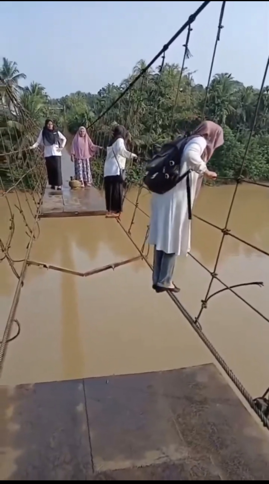 Perjuangan guru SD saat menyebrangi sungai lewat jembatan gantung yang rusak.