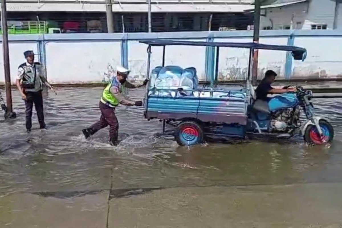Polisi mendorong motor roda tiga yang mogok ditengah jalan raya Pantura Sayung.(Wahib&nbsp;Pribadi)