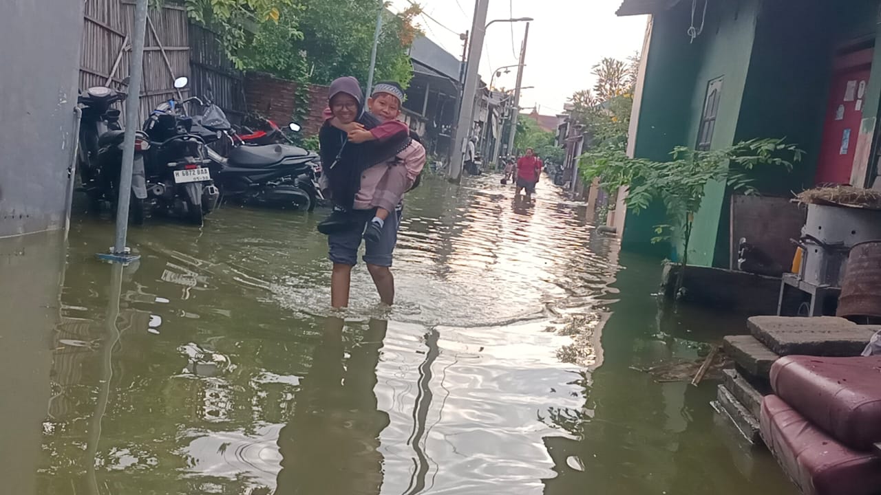 Warga Tambakrejo menggendong anaknya terjang banjir, Rabu (22/10).