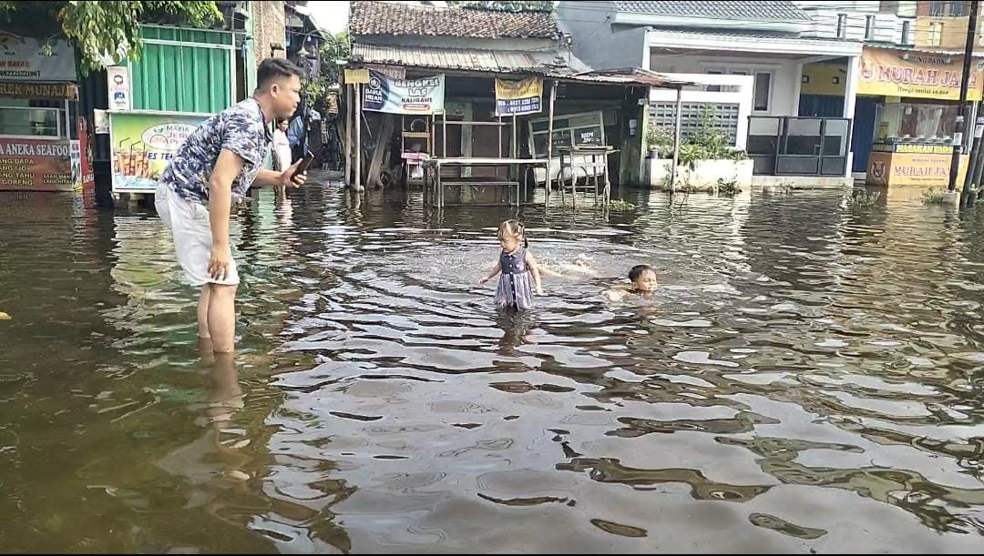 Anak-anak diawasi orang tuanya bermain di banjir Kaligawe, Minggu (26/10). (Dokumentasi Figur Ronggo Wassalim/Jawa Pos Radar Semarang)