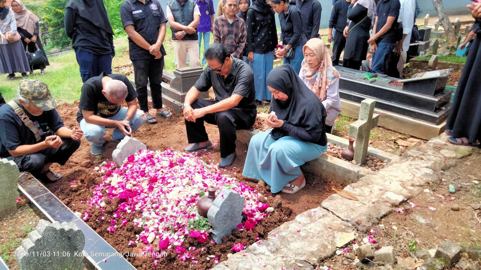 Warga binaan pemasyarakatan Lapas Perempuan Semarang berinisial LD (baju hitam rok biru) dikawal petugas menghadiri pemakaman suami di Kelurahan Sampangan, Kota Semarang, Senin (3/11/2025).