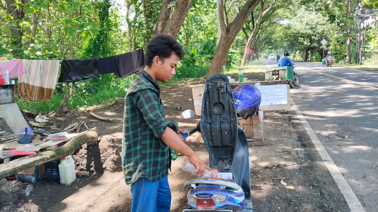 LAYANI PEMBELI - Agung saat melayani salah satu pembeli bensin di lapaknya yang sangat sederhana di jalur alas Roban Batang.