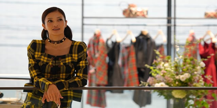 Tangkapan layar dari akun Instagram meisa_kuroki_, menampilkan Meisa Kuroki yang berdiri anggun di dalam sebuah butik dengan latar gantungan busana. Ia mengenakan gaun bermotif kotak bernuansa kuning.