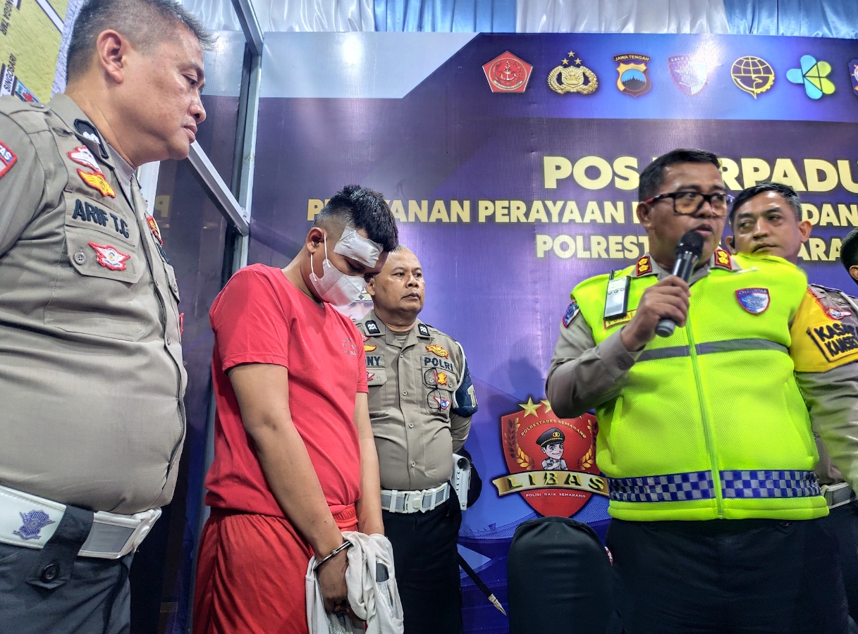 Tersangka sopir bus cahaya trans Gilang Ihsan Faruq mengenakan baju merah dan tangan terborgol