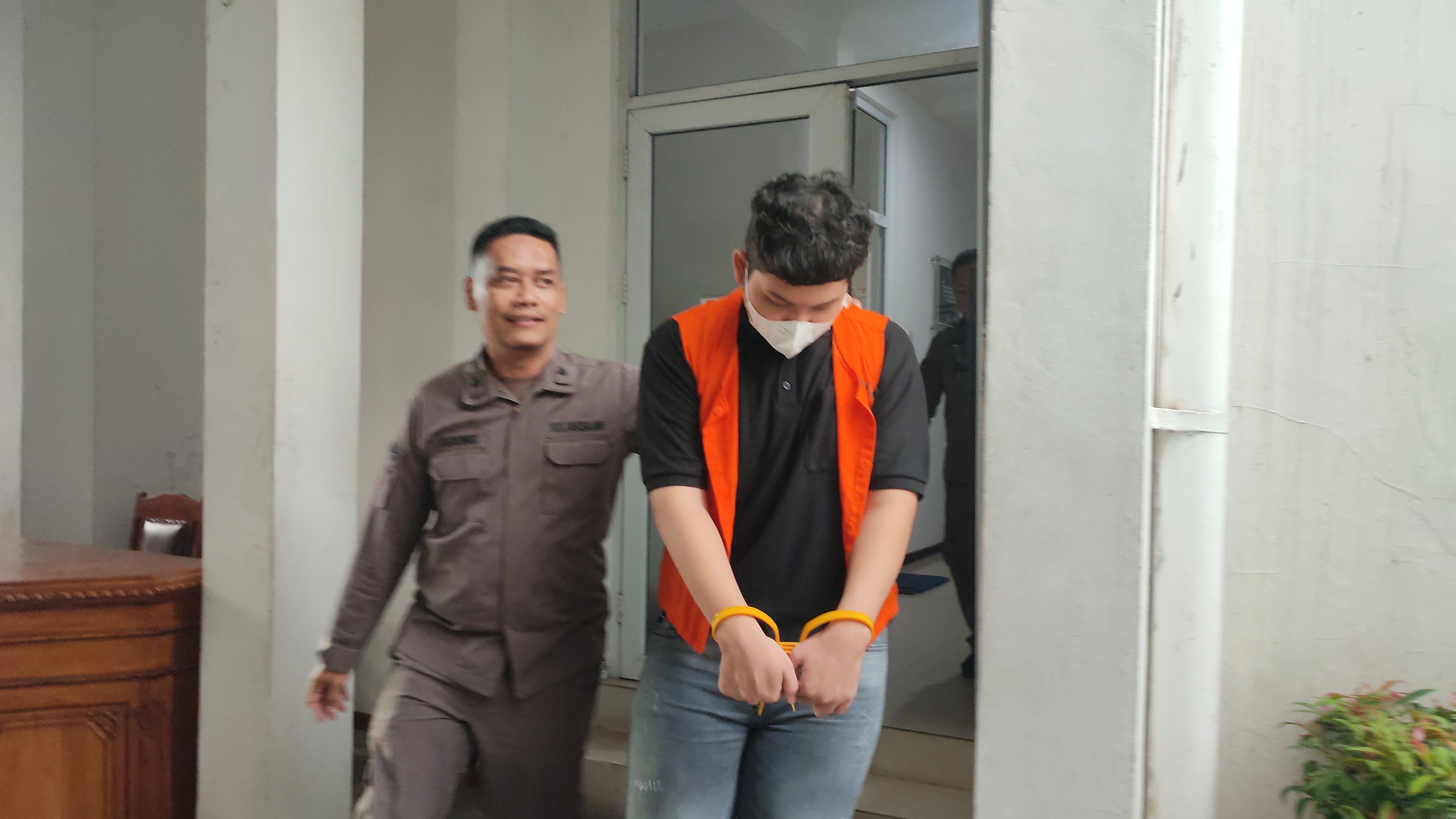 Tersangka kasus pornografi berbasis AI, Chiko Raditya Agung Putra berjalan menunduk saat digelandang ke Lapas Semarang usai dilimpahkan ke Kejari Kota Semarang, Kamis (8/1/2025).
