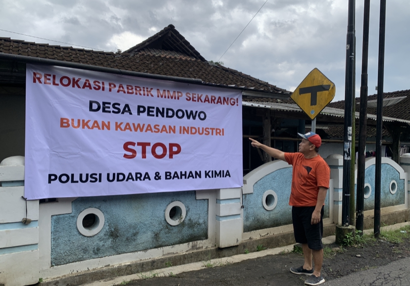 Seorang warga menunjukkan spanduk bentuk protes terhadap pabrik MMP yang menimbulkan polusi udara.