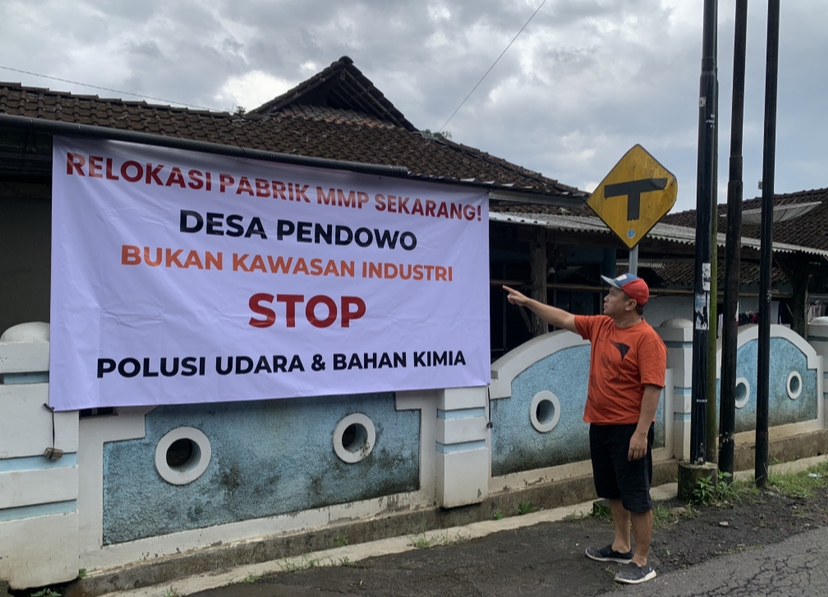Seorang warga Desa Pendowo, Kranggan, saat menunjukkan spanduk protes terhadap operasional pabrik MMP yang diduga mencemari lingkungan.