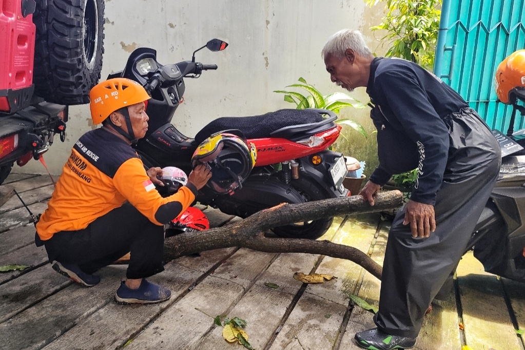 Sepeda motor warna merah, helm dan batang pohon yang menimpa korban