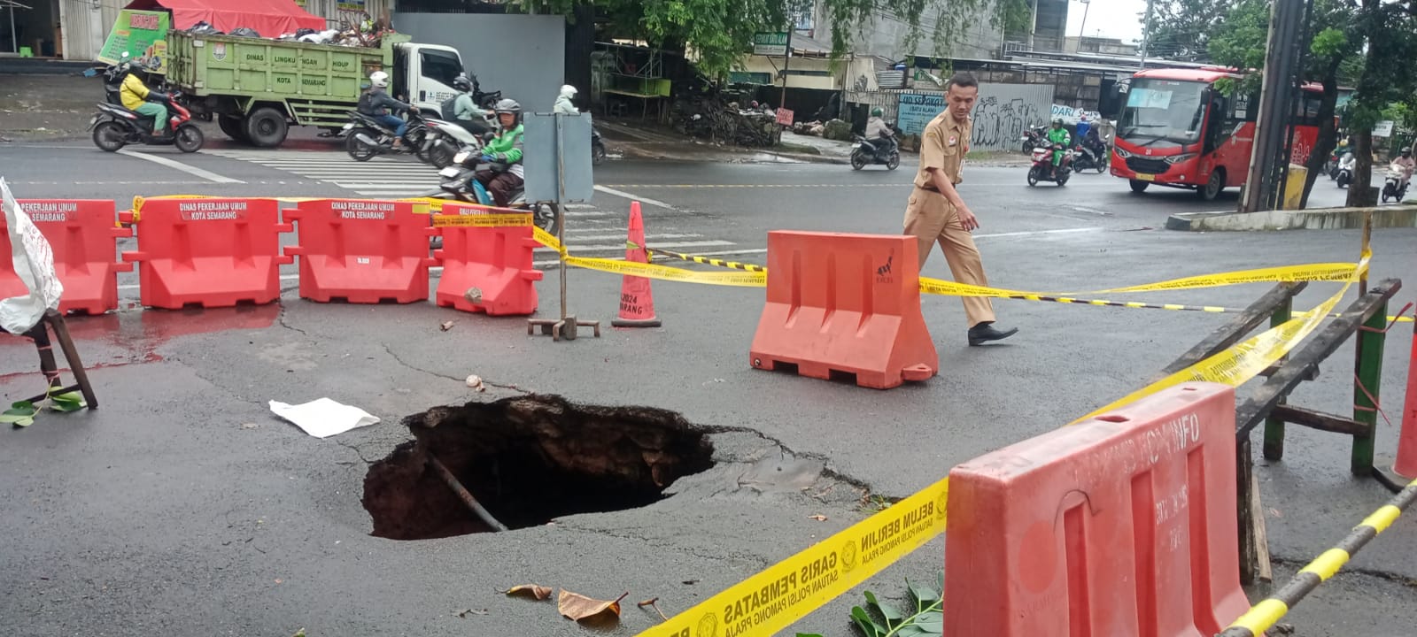Seorang PNS melintas di depan jalan yang ambles di tepi Jl.Dr Wahidin,Semarang. (Sulistiono)