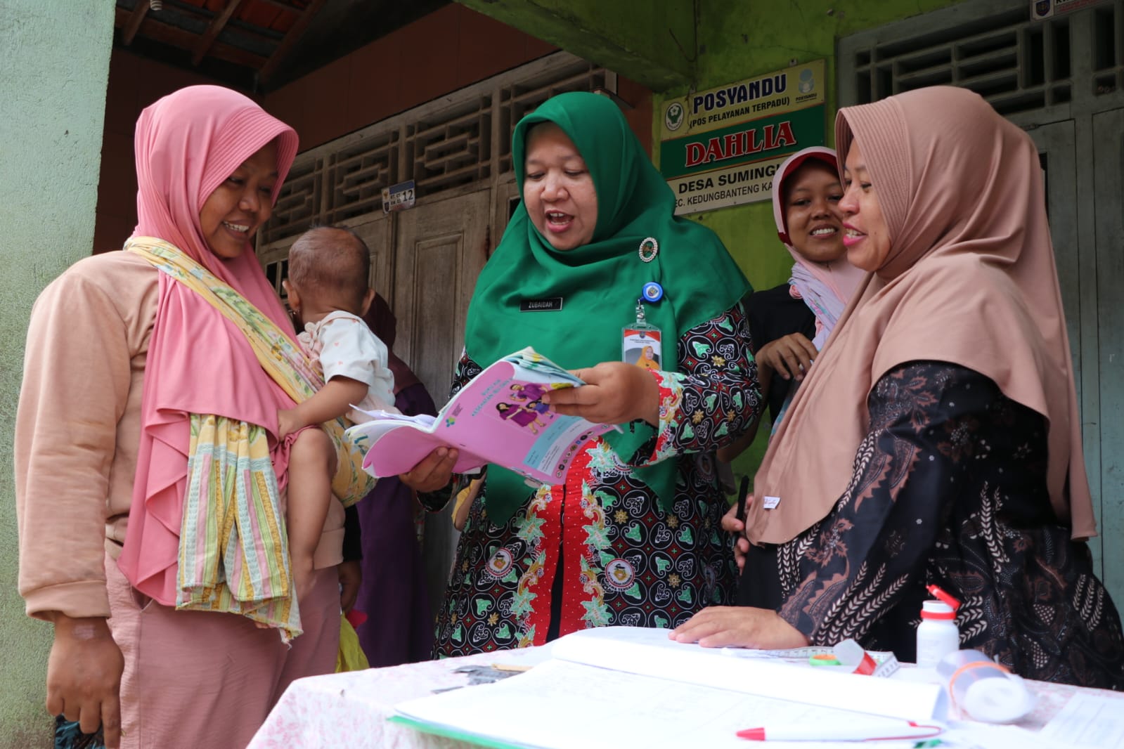 Programmer KIA Puskesmas Kedungbanteng, Kabupaten Tegal, Zubaidah (kerudung hijau) ketika menjelaskan Program Stimulasi Dini tentang stimulasi anak usia dini di Posyandu Dahlia.