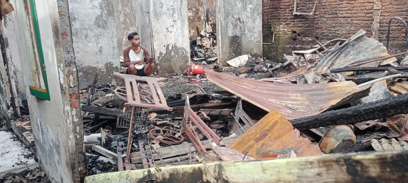 Andika, pemilik rumah yang terbakar , tercenung menyaksikan puing-puing rumahnya. (Sulistiono)