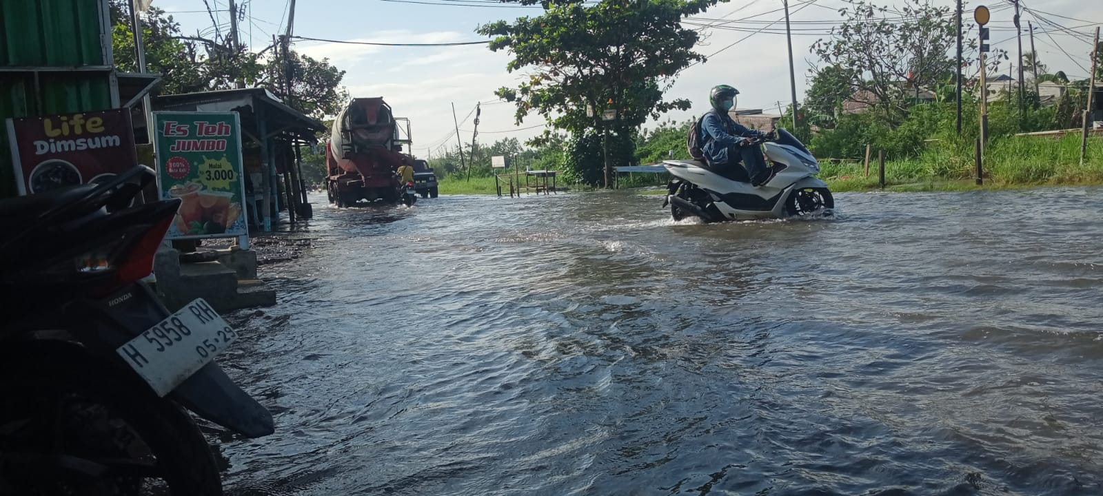 Pengendara motor tengah melintas ditengah genangan banjir dikawasan Jalan Muktiharjo Raya. (Sulistiono)