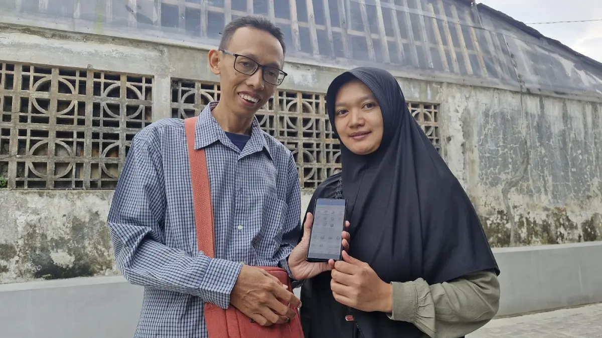 Nanik Agustina bersama sang suami menunjukkan aplikasi Mobile JKN. (PUPUT PUSPITASARI/JAWA POS RADAR SEMARANG)