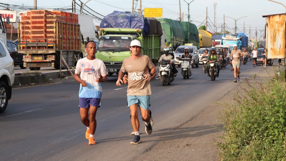 Sam co Founder Sungai Watch (bertopi putih) saat berlari melintasi pantura Pekalongan menuju Pemalang beberapa hari kemarin. (Lutfi Hanafi/Jawa Pos Radar Semarang)