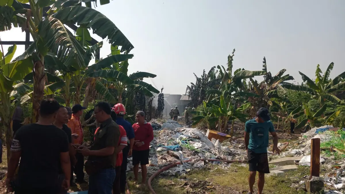 Petugas Damkar dibantu warga tengah memadamkan titik api yang masih tersisa dilokasi terbakarnya bekas gudang rongsok di Banjardowo. (Ist)