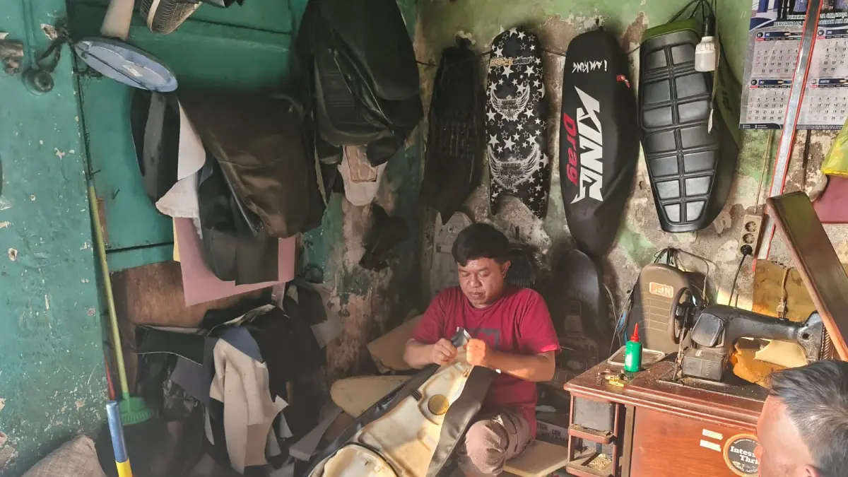 Subagyo saar memasang kulit jok motor 