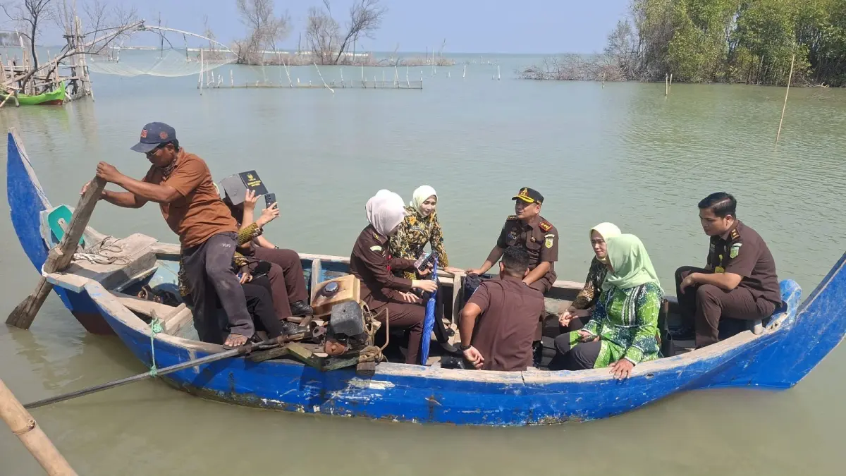 Kejari Demak Milono Raharjo SH dan istri menyerahkan bantuan korban rob di Timbulsloko Sayung dengan naik perahu. (Wahibpribadi)