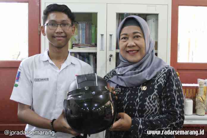 INOVATIF: Adira Danuarta bersama guru pembimbing Ristavo Student Company Titi Priyatiningsih menunjukkan helm berpanel surya. (ALVI NUR JANAH/JAWA POS RADAR SEMARANG)