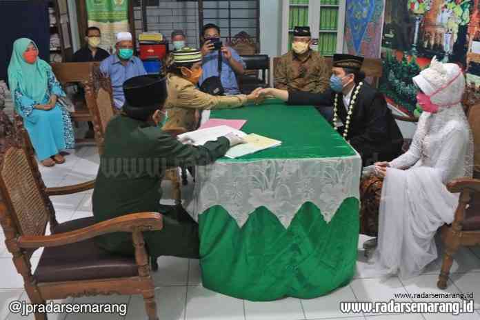 Pasangan pengantin Victor Nur Fendi dan Fatih Adini Rinoga saat melangsungkan ijab kabul dengan mengenakan masker di KUA Semarang Barat, Minggu  (19/4/2020). (Nurchamim/Jawa Pos Radar Semarang)