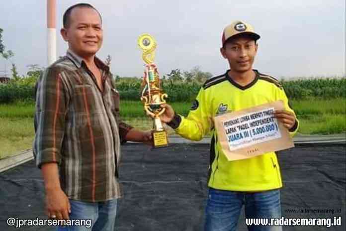 M Joned (kuning) saat menerima tropi kejuaraan merpati kolong. (Istimewa)